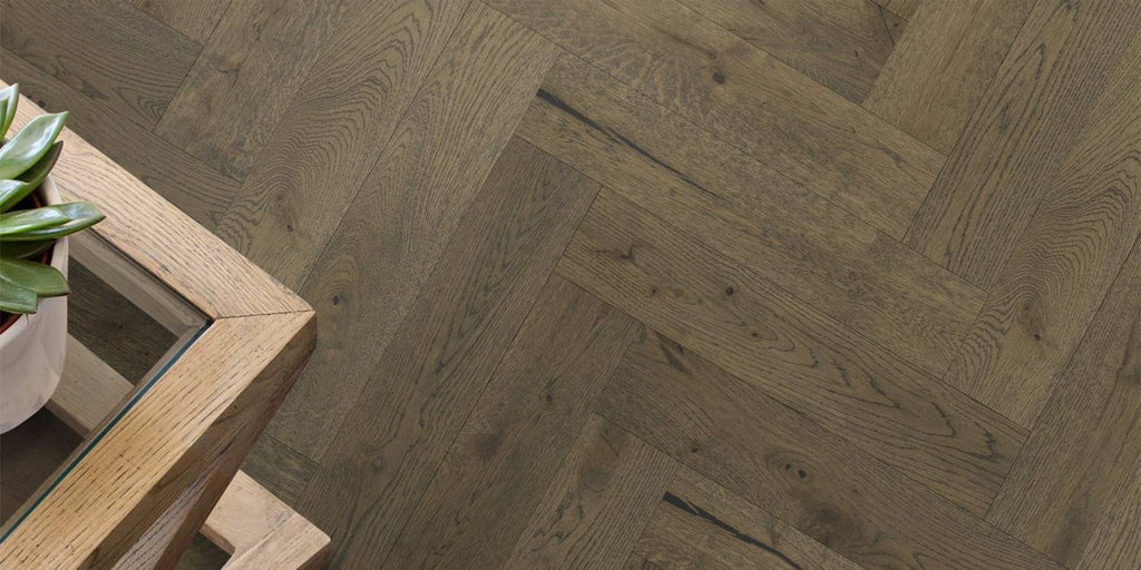 Wooden floor with herringbone pattern and a small table with a plant.
