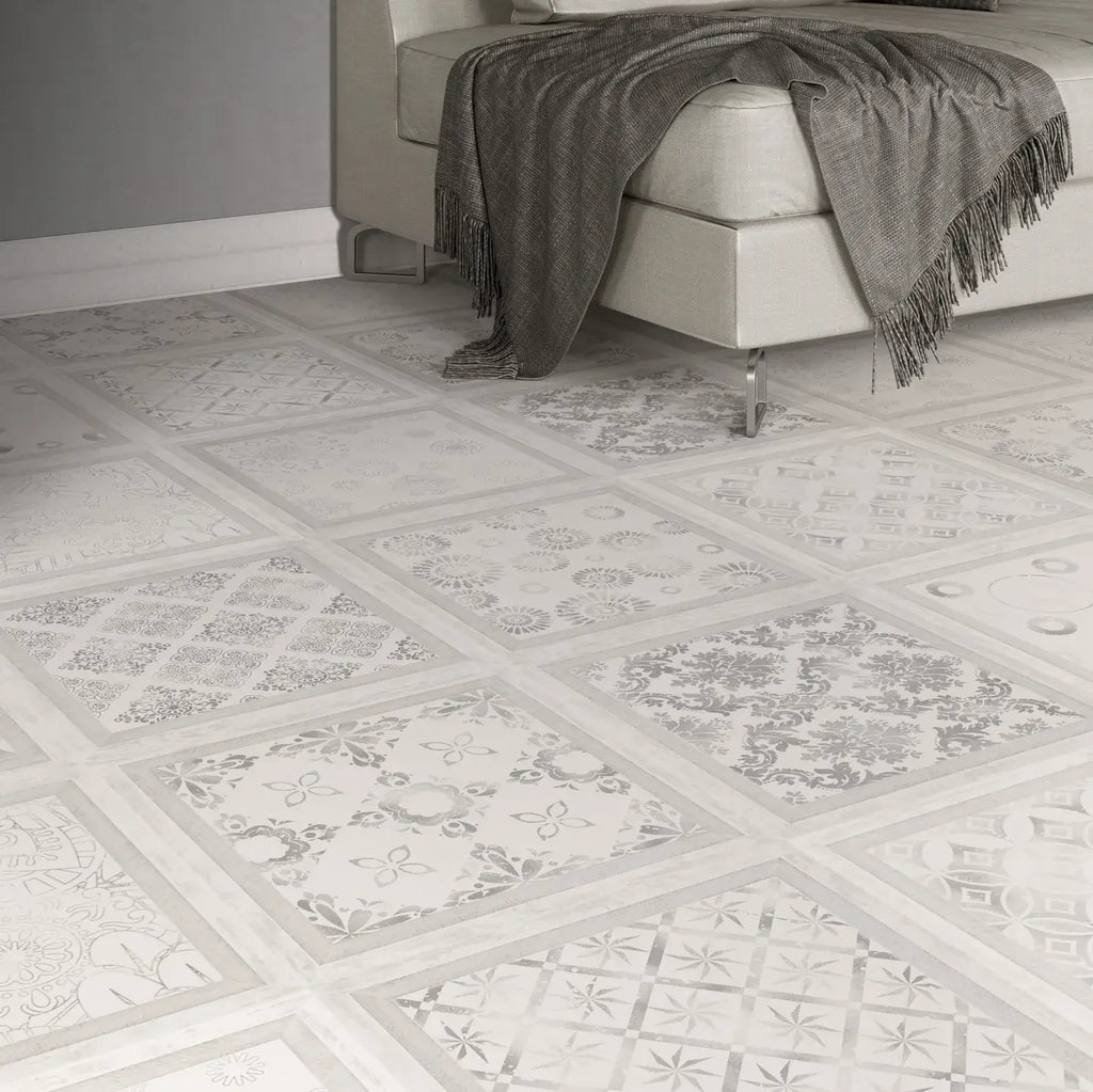 Decorative square floor tiles with a white and gray mosaic pattern, shown in a modern room setting with a light-colored sofa and a gray throw blanket.