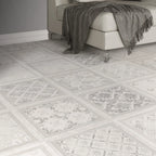 Decorative square floor tiles with a white and gray mosaic pattern, shown in a modern room setting with a light-colored sofa and a gray throw blanket.