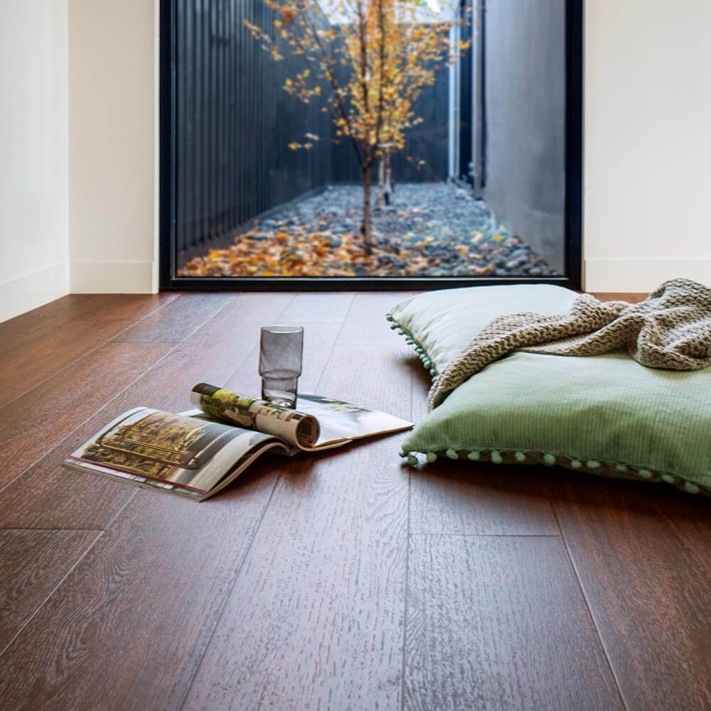 Flooring with a magazine, glass, and pillows in a room with a large window.