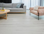Living room with gray sofa, pink armchair, and wooden coffee table on a light wood floor.