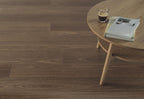 Wooden floor with a small round table and a glass of dark liquid on it.