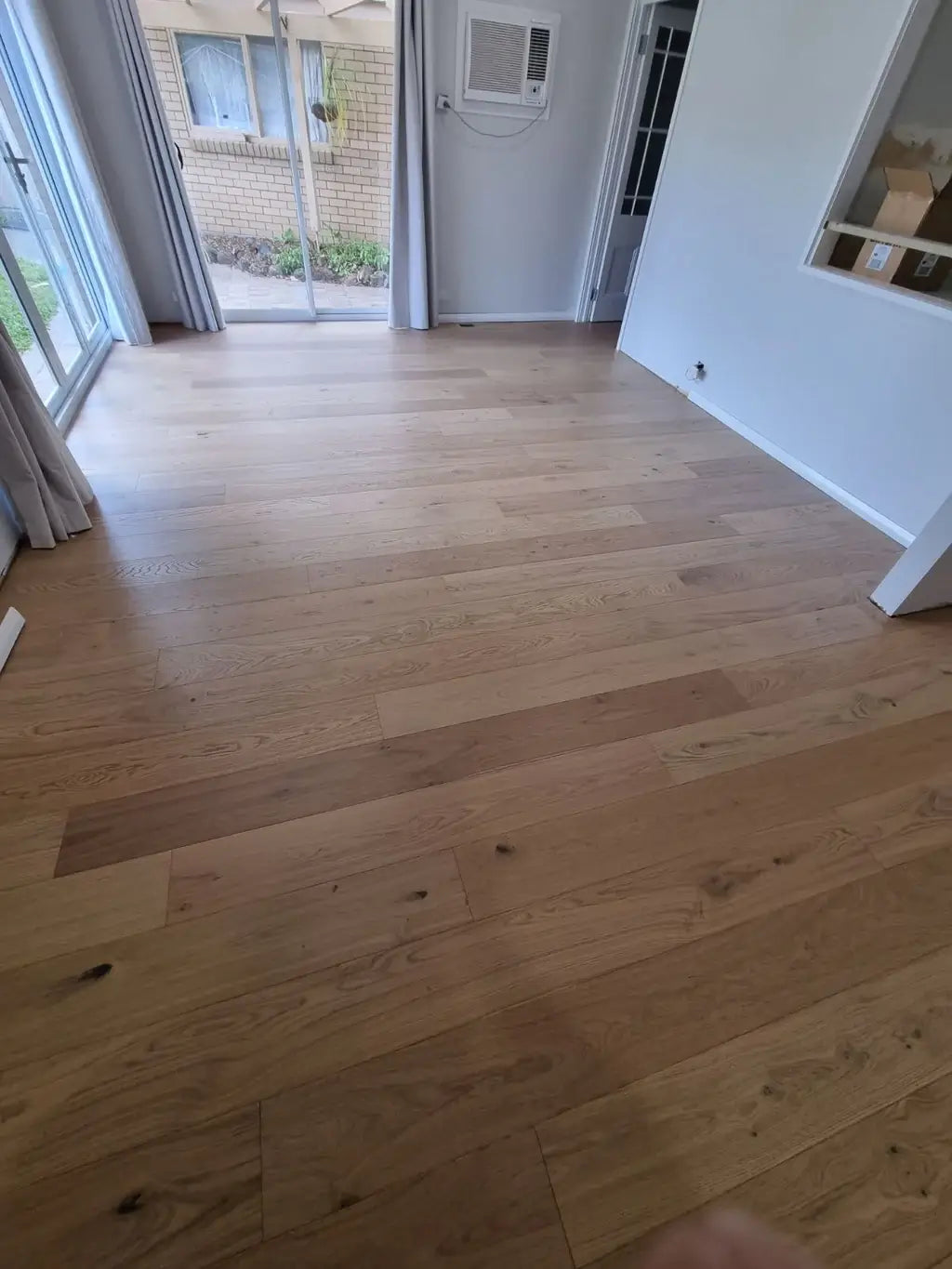 Wooden floor in a room with a sliding glass door and white walls.