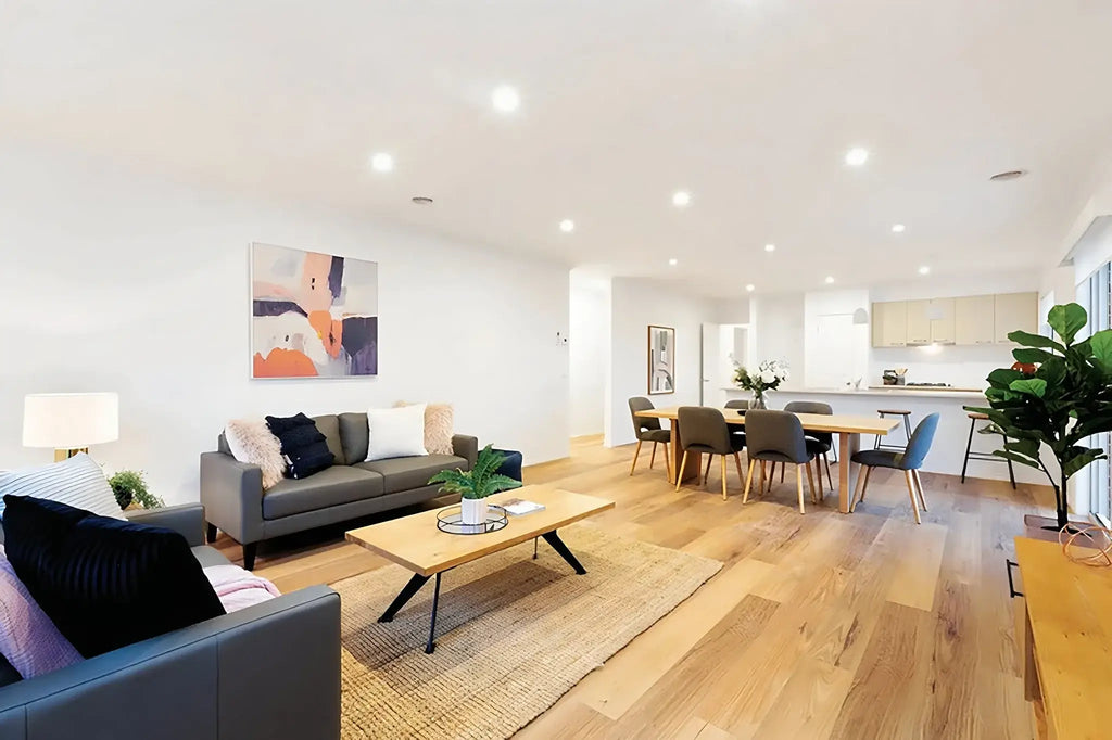Modern living room with gray sofa, coffee table, and dining area.