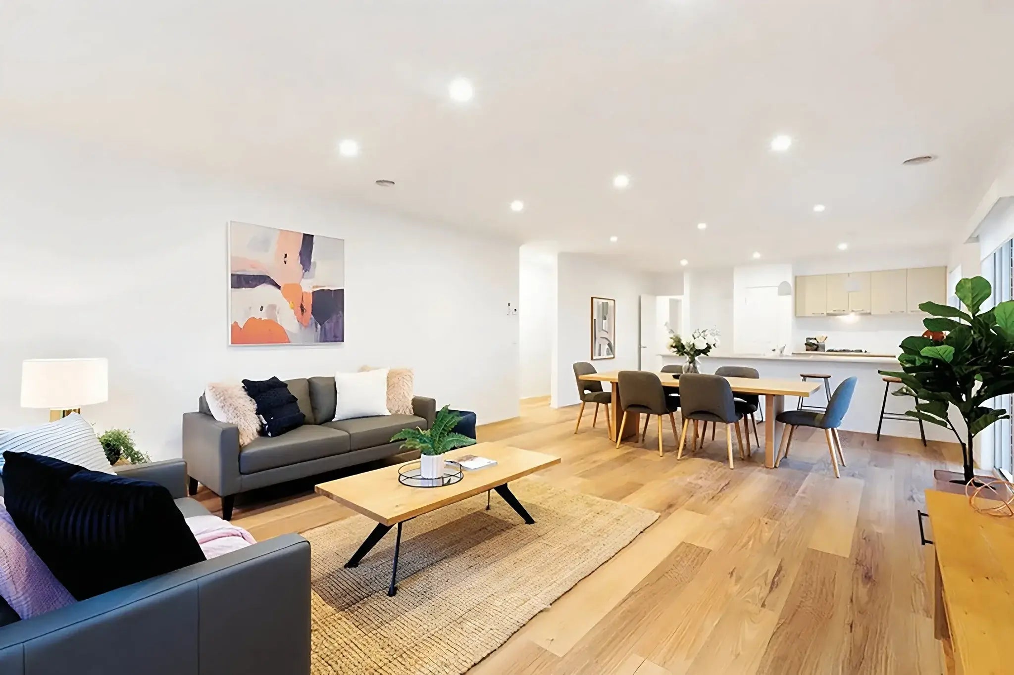 Modern living room with gray sofa, coffee table, and dining area.