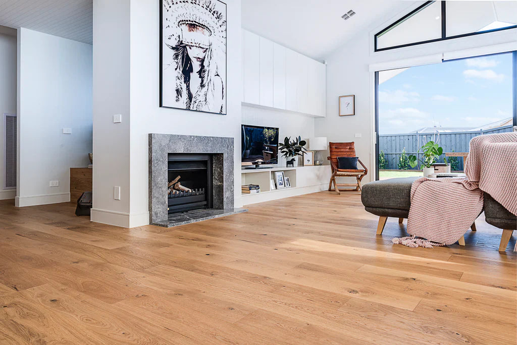 Modern living room with wooden flooring, fireplace, and large windows.